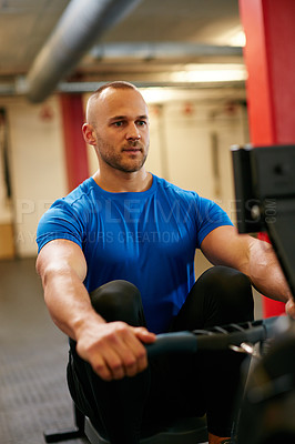 Buy stock photo Cropped shot of a young man working out on the rowing machine at the gym
