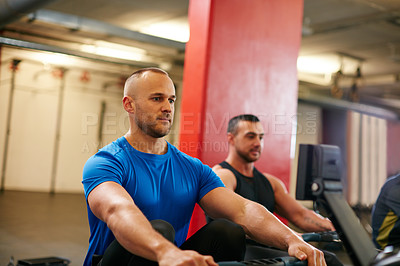 Buy stock photo Cropped shot of two men working out on the rowing machine at the gym