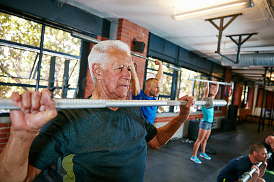 Buy stock photo Shot of a senior man working out in a health club with people blurred in the background