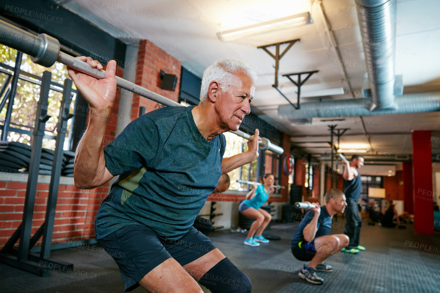 Buy stock photo Shot of a senior man working out in a health club with people blurred in the background