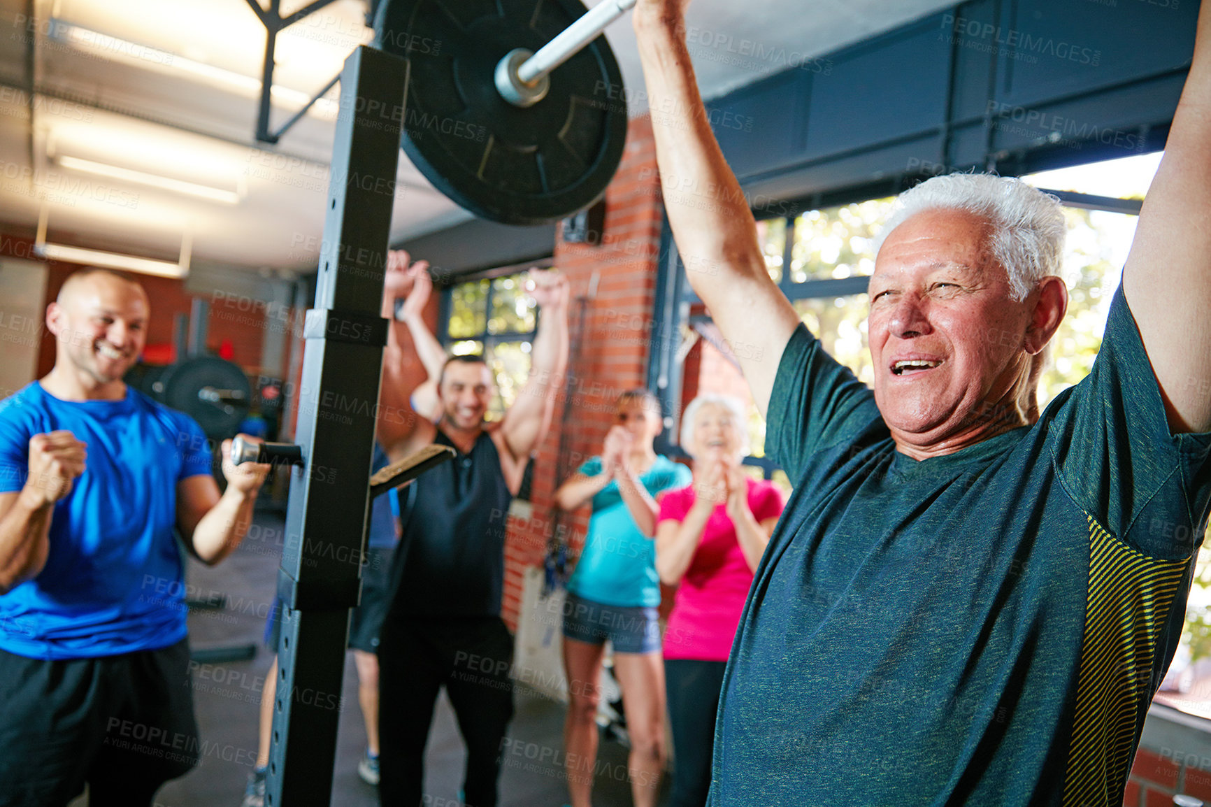 Buy stock photo Shot of a senior man lifting weights while a group of people in the background watch on