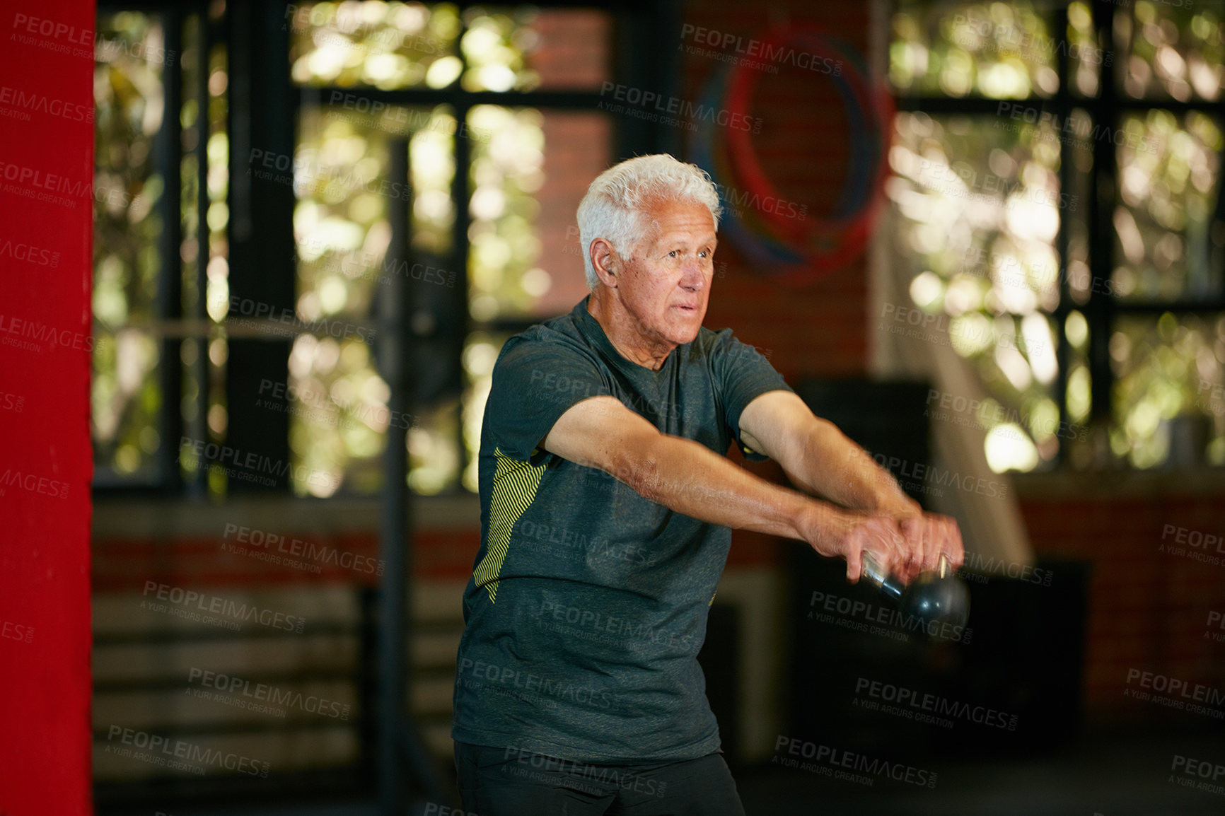 Buy stock photo Shot of a senior man working out with a kettle bell at the gym