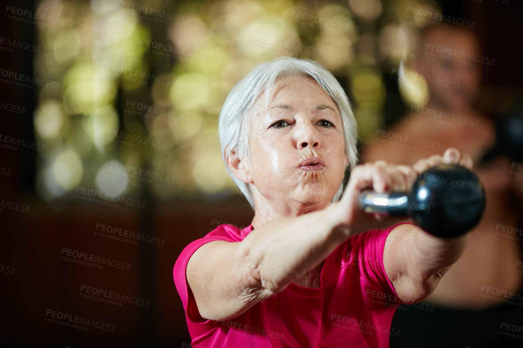 Buy stock photo Shot of a senior woman working out with a kettle bell at the gym