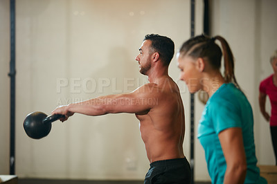 Buy stock photo Shot of a shirtless young man working out with a kettle bell at the gym