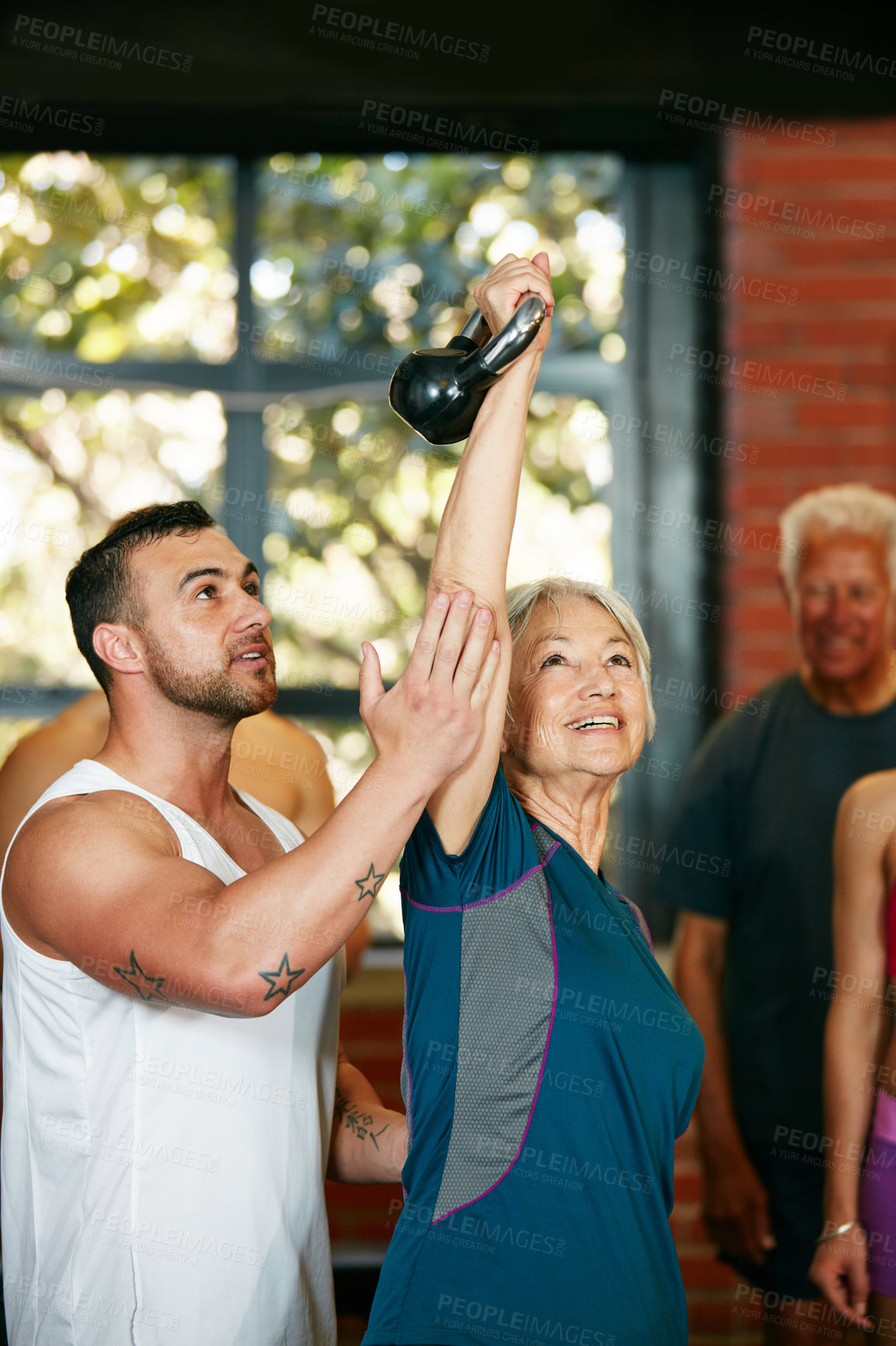 Buy stock photo Shot of a trainer motivating a senior woman during her kettle bell workout at the gym