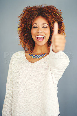 Buy stock photo Portrait of a young woman showing thumbs up against a grey background