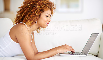 Buy stock photo Shot of a young woman using a laptop on the sofa at home