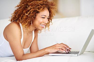 Buy stock photo Shot of a young woman using a laptop on the sofa at home