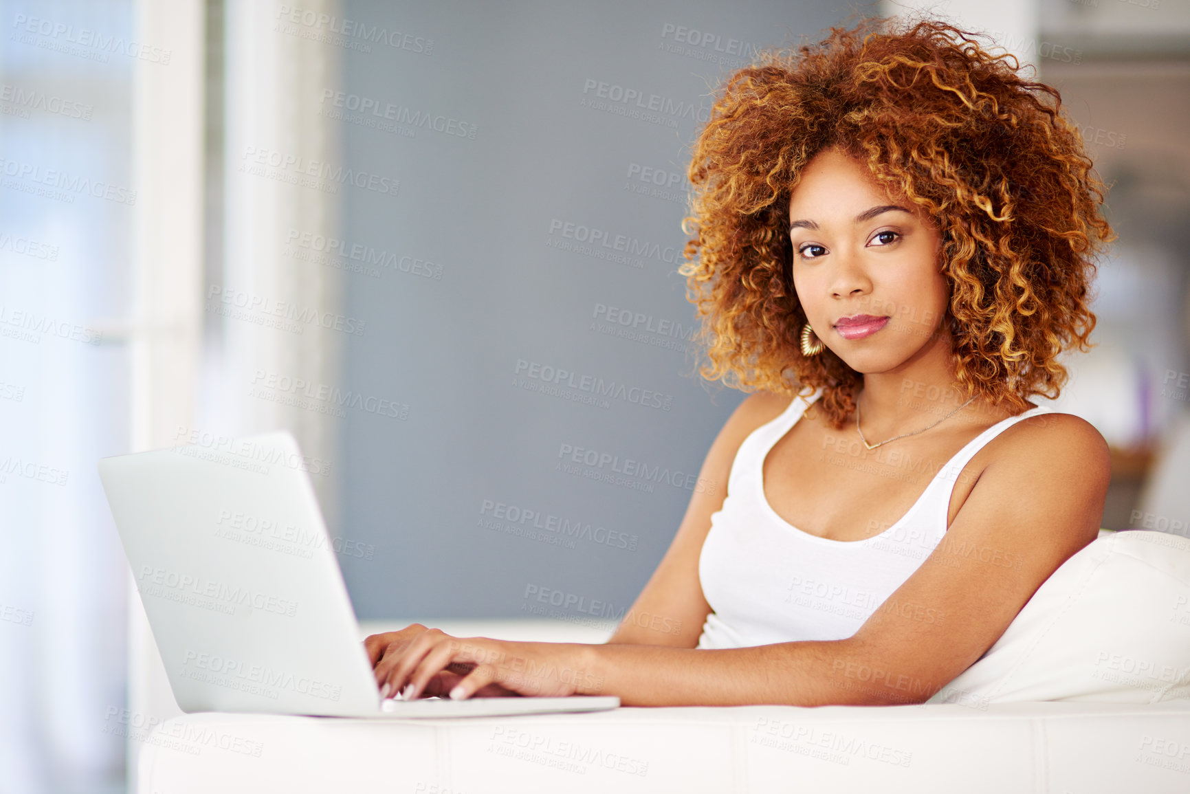 Buy stock photo Portrait of a young woman using a laptop on the sofa at home