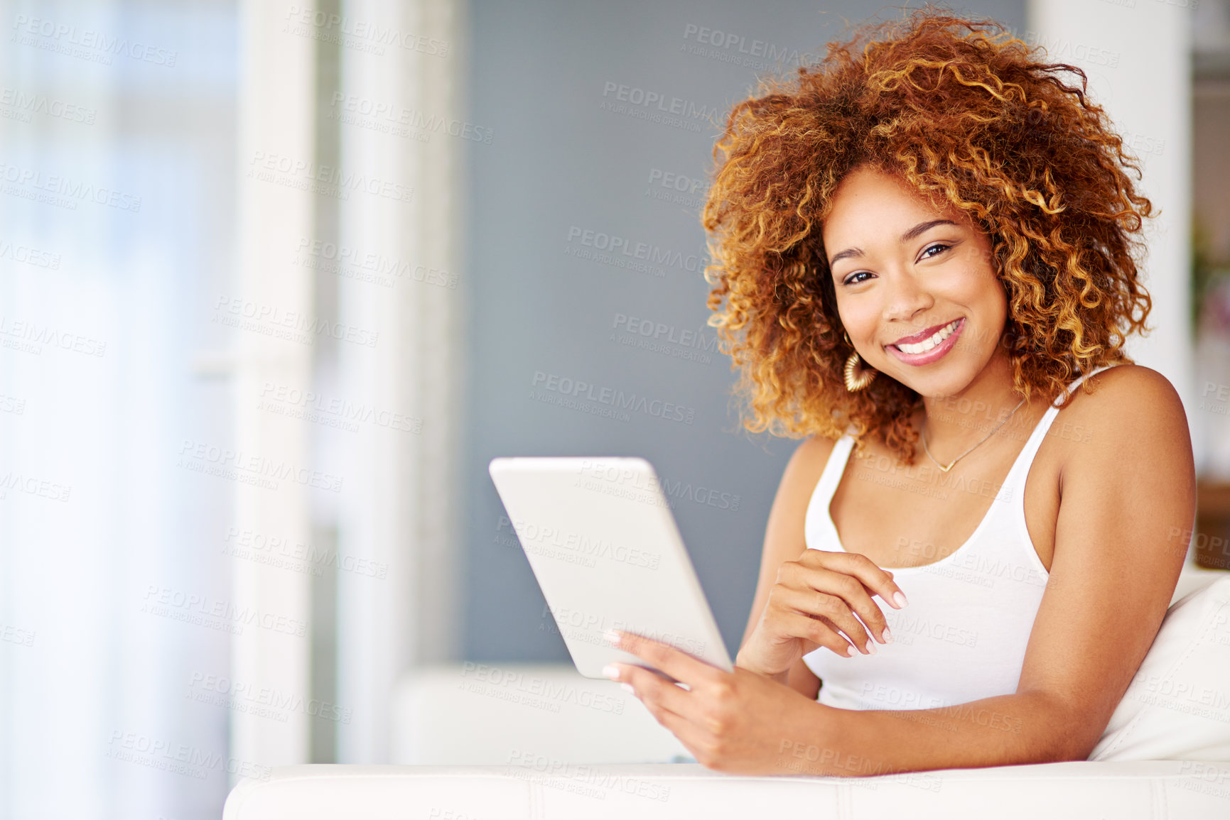 Buy stock photo Portrait of a young woman using a digital tablet on the sofa at home