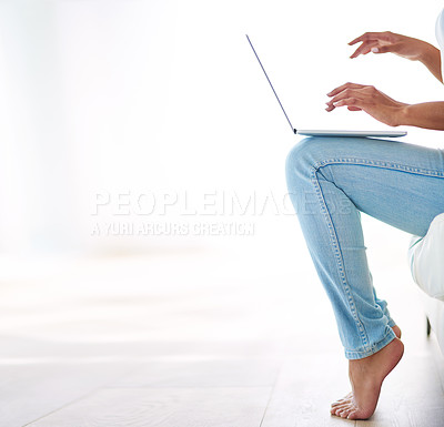 Buy stock photo Cropped shot of a woman using a laptop on the sofa at home