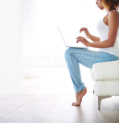 Buy stock photo Cropped shot of a young woman using a laptop on the sofa at home