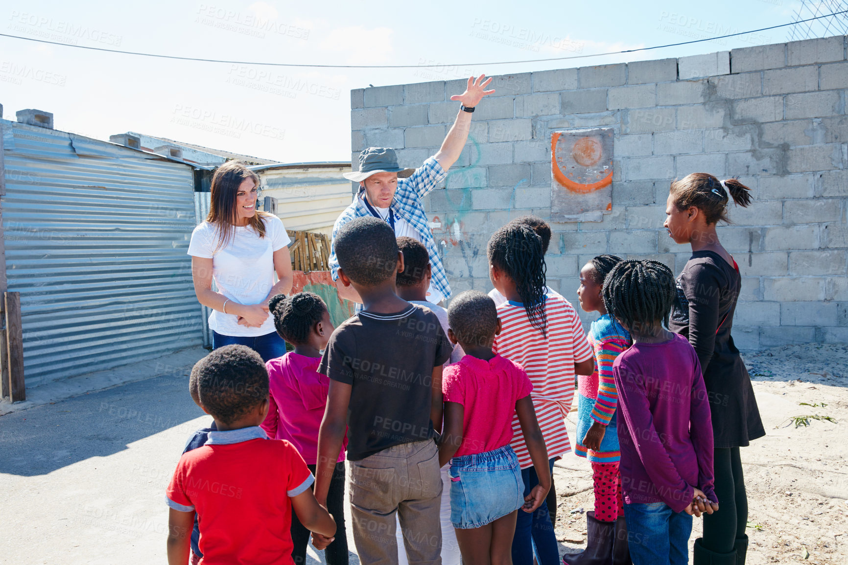 Buy stock photo Shot of two volunteer workers addressing a group of kids at a community outreach event