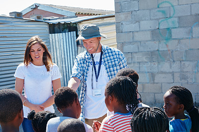 Buy stock photo Shot of two volunteer workers addressing a group of kids at a community outreach event