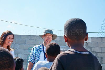 Buy stock photo Shot of two volunteer workers addressing a group of kids at a community outreach event