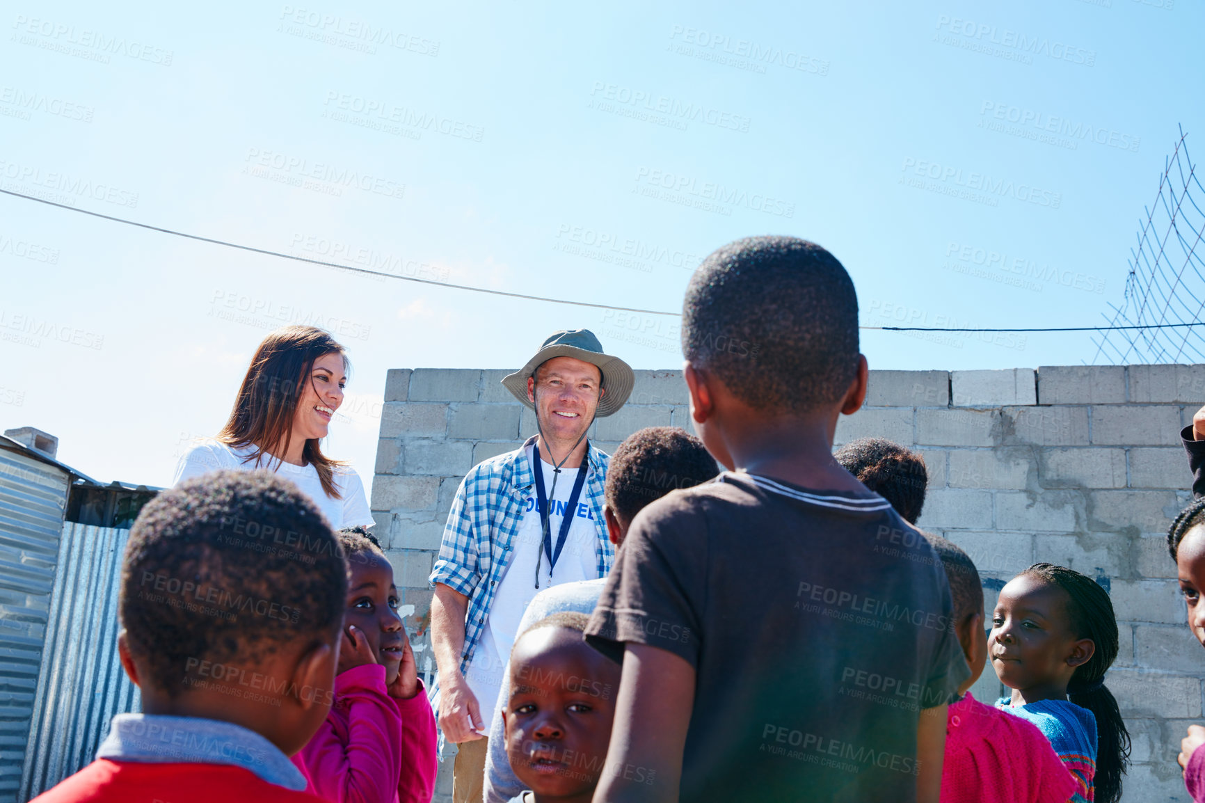 Buy stock photo Shot of two volunteer workers addressing a group of kids at a community outreach event