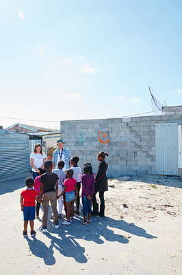 Buy stock photo Shot of two volunteer workers addressing a group of kids at a community outreach event