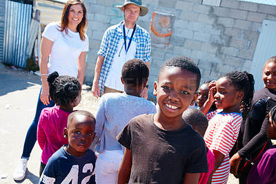 Buy stock photo Shot of two volunteer workers addressing a group of kids at a community outreach event