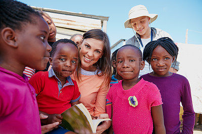 Buy stock photo Cropped shot of a volunteer worker reading to a group of children at a community outreach event