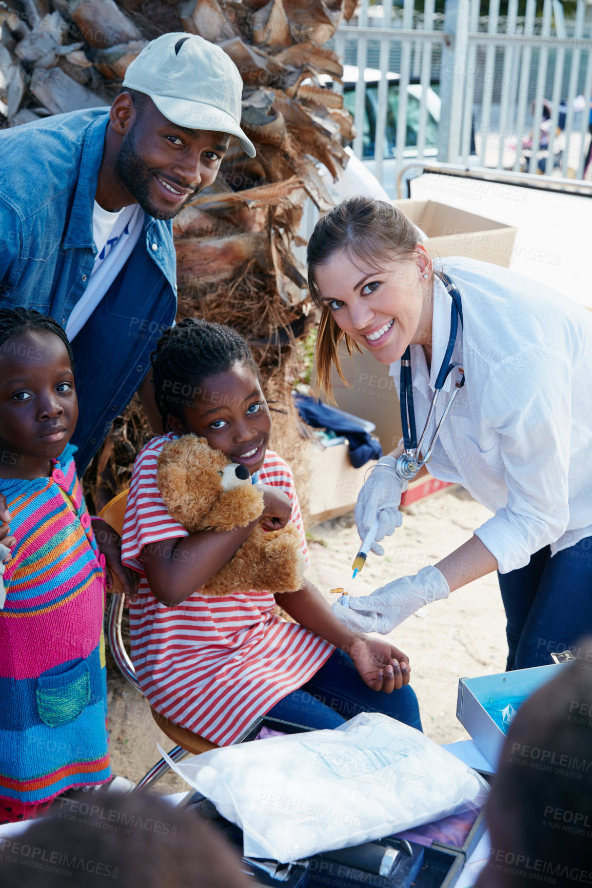 Buy stock photo Shot of a volunteer nurse giving injections to underprivileged kids