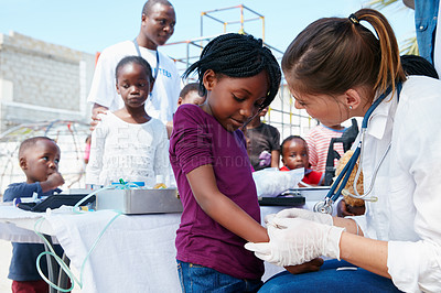 Buy stock photo Cropped shot of volunteer nurses giving checkups to underprivileged kids