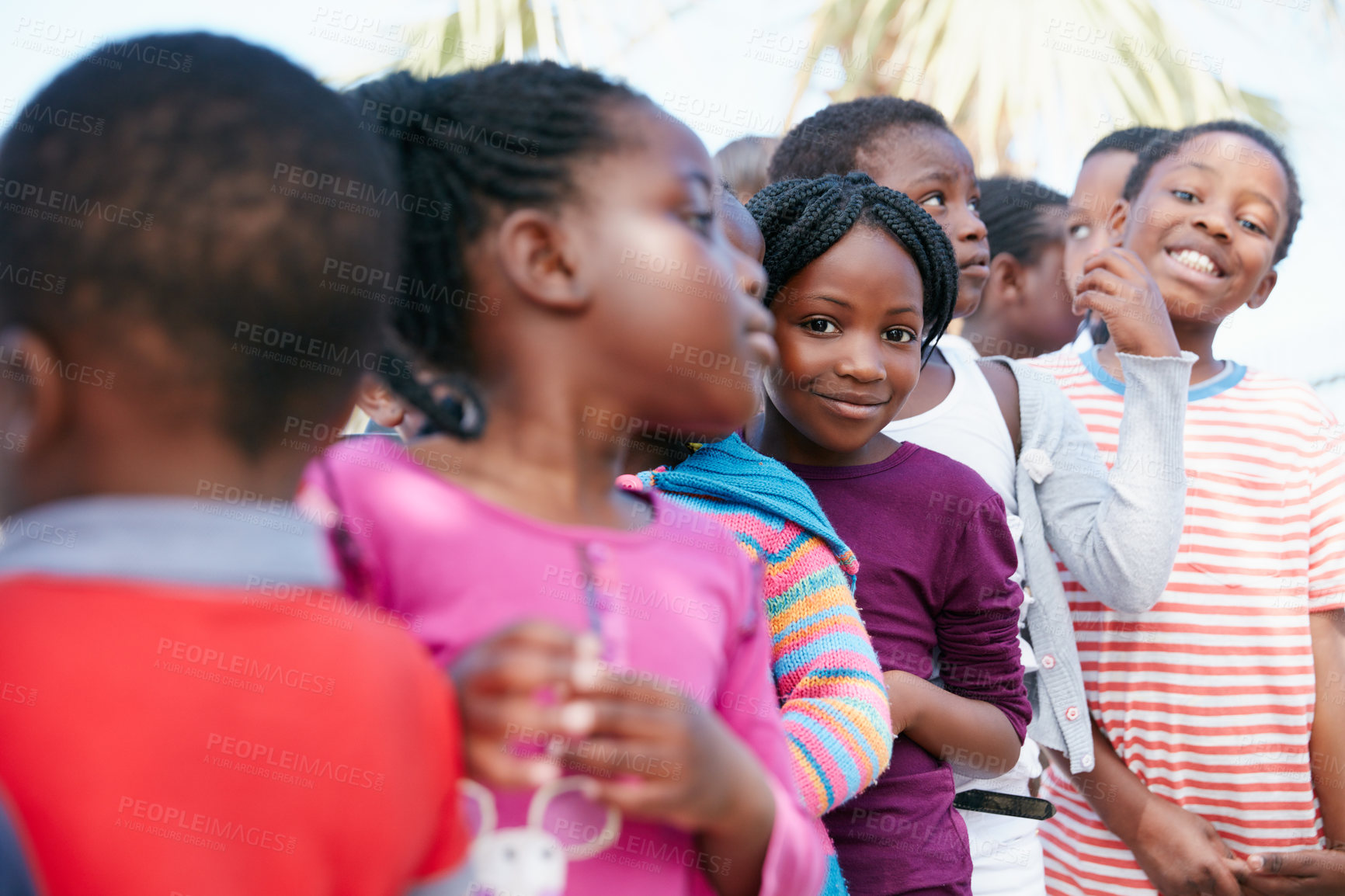 Buy stock photo Children, row and smile in portrait at community outreach event, excited or poverty relief at park. African kids, girl and boy in line, happy and group with charity drive, program or humanitarian aid
