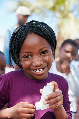 Buy stock photo Portrait of a little girl holding an asthma inhaler at a community outreach event