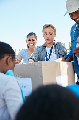 Buy stock photo Cropped shot of volunteer workers handing out clothing to underprivileged children 