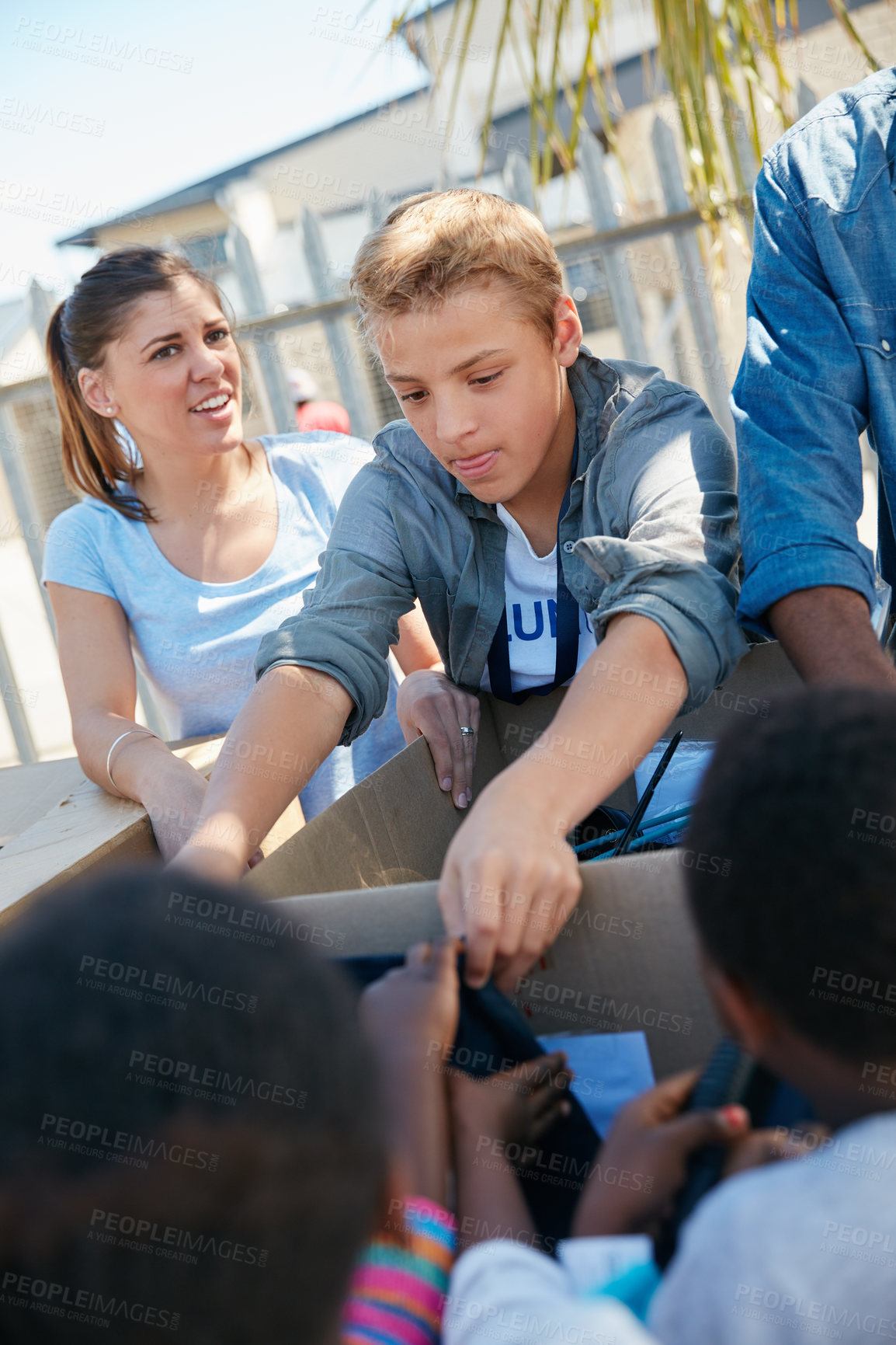 Buy stock photo Cropped shot of volunteer workers handing out clothing to underprivileged children 