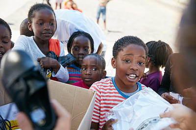 Buy stock photo Cropped shot of volunteer workers handing out clothing to underprivileged children 
