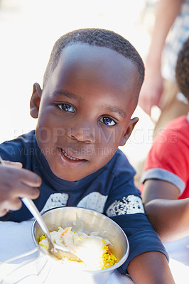 Buy stock photo Cropped portrait of a young boy getting fed at a food outreach