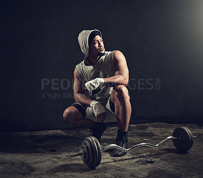 Buy stock photo Full length shot of an athletic young man crouching down besides weights against a dark background