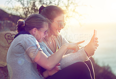 Buy stock photo Cropped shot of two teenage girls reading an sms outdoors