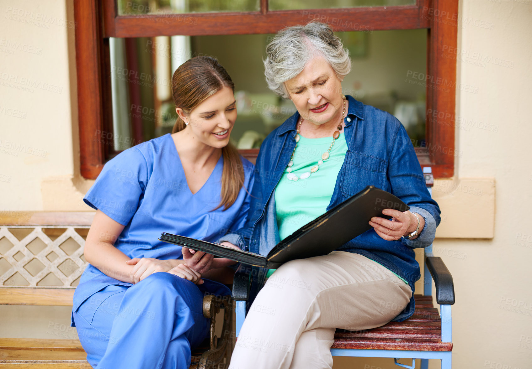 Buy stock photo Shot of a resident and a nurse looking through a photo album