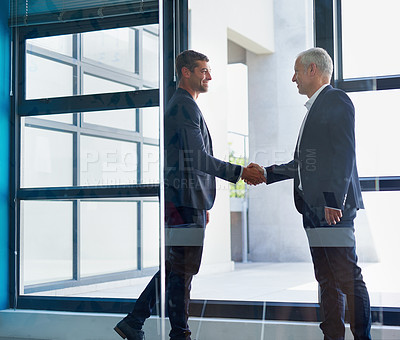 Buy stock photo Cropped shot of two businessmen shaking hands in the lobby