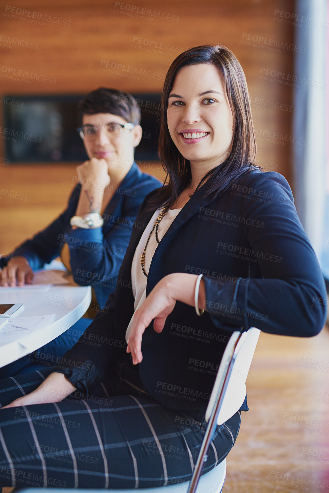 Buy stock photo Cropped portrait of a businesswoman sitting in the boardroom with a colleague in the background