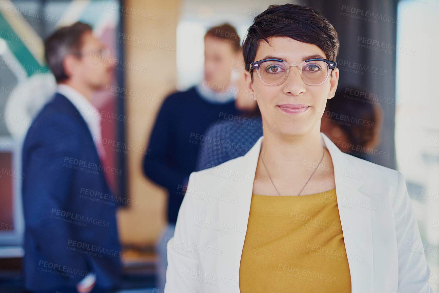 Buy stock photo Cropped portrait of a businesswoman standing in the office with her colleagues in the background