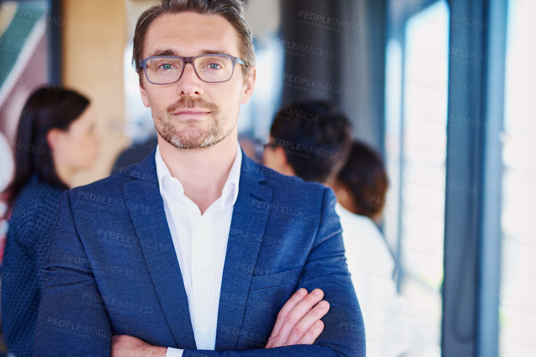 Buy stock photo Cropped portrait of a businessman standing in the office with his colleagues in the background