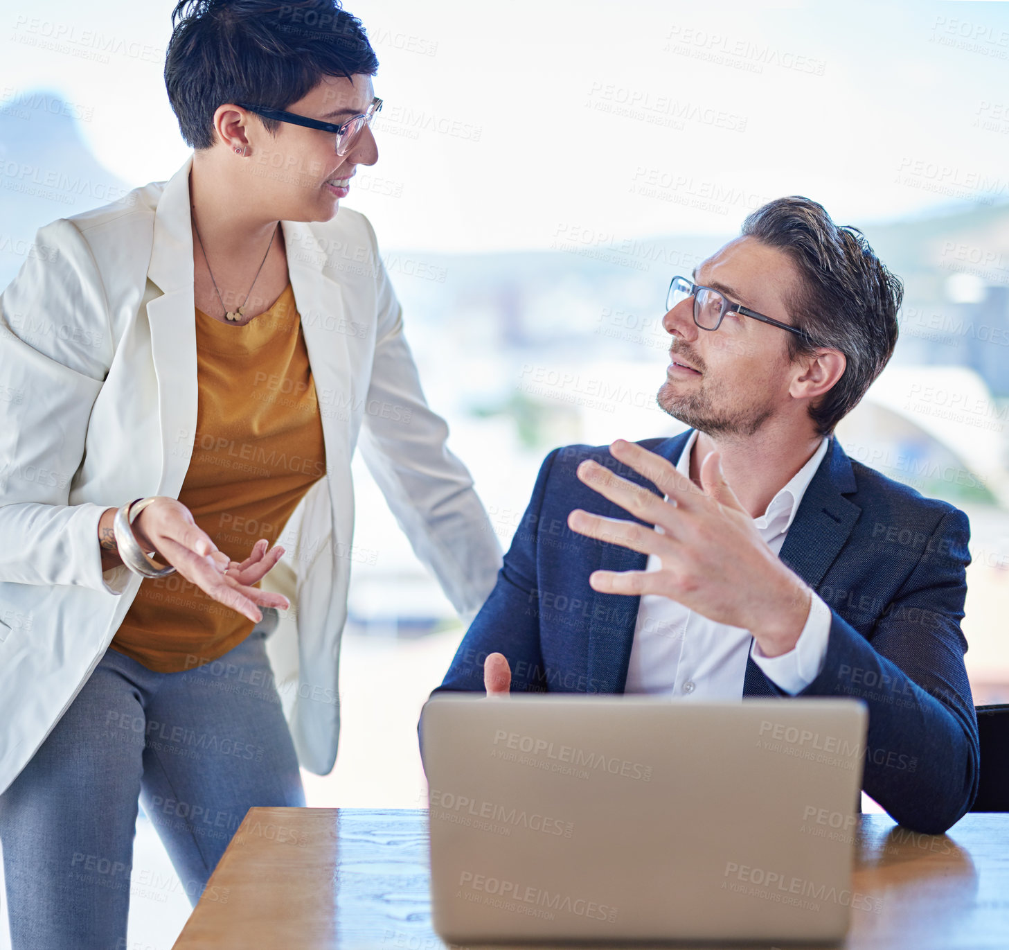 Buy stock photo Shot of two colleagues working on a laptop at a desk in an office