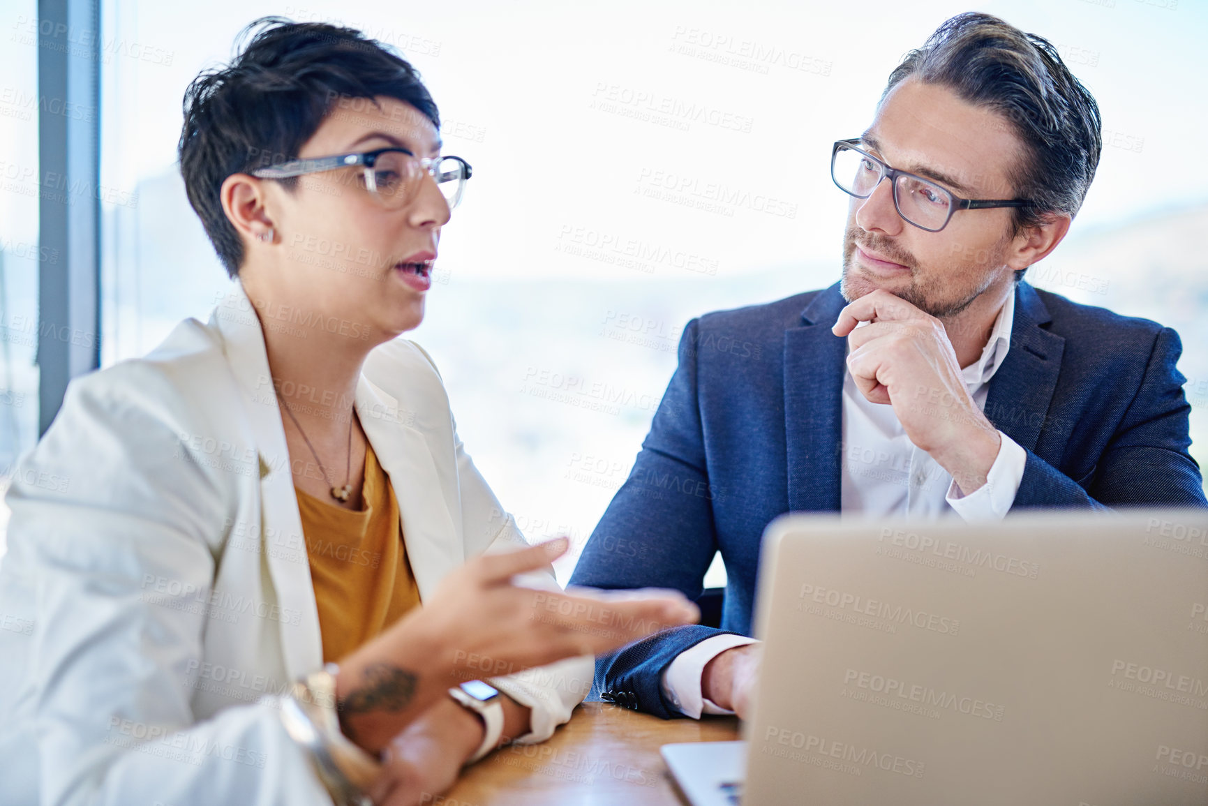 Buy stock photo Shot of two colleagues working on a laptop at a desk in an office