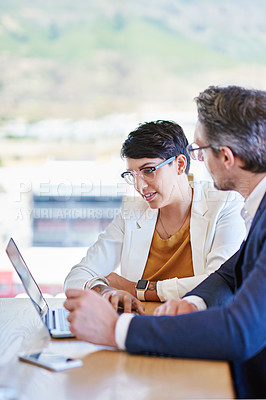 Buy stock photo Shot of two colleagues working on a laptop at a desk in an office