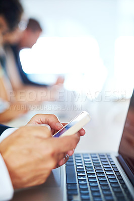 Buy stock photo Cropped shot of a businessman using his phone and laptop in an office