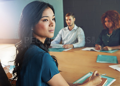 Buy stock photo Shot of a businesswoman sitting in a meeting with her colleagues blurred in the background