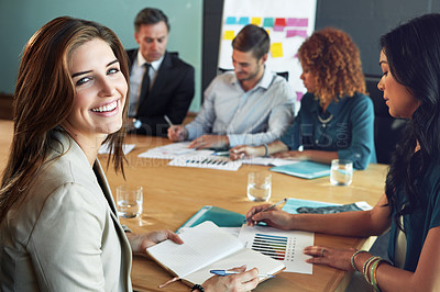 Buy stock photo Portrait of a businesswoman sitting in a meeting with her colleagues blurred in the background