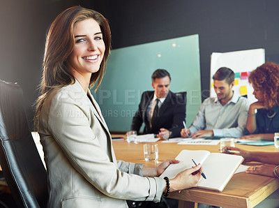 Buy stock photo Portrait of a businesswoman sitting in a meeting with her colleagues blurred in the background