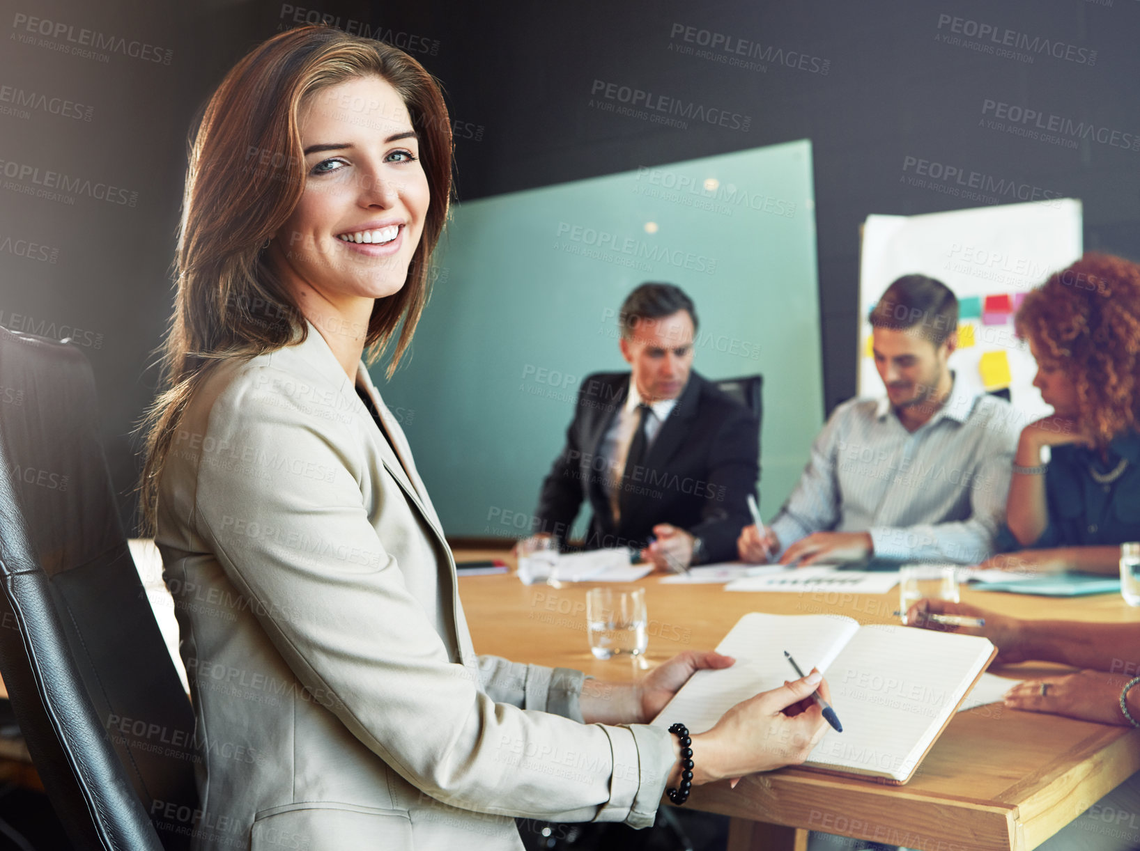 Buy stock photo Portrait of a businesswoman sitting in a meeting with her colleagues blurred in the background