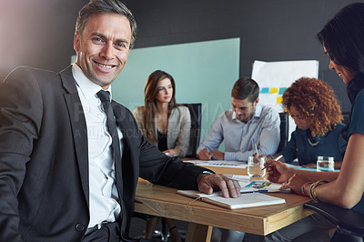 Buy stock photo Portrait of a businessman in a meeting with his colleagues in the background