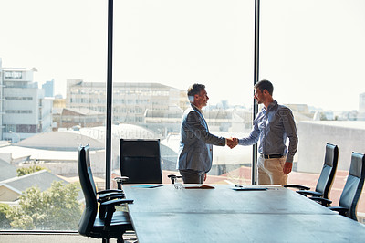Buy stock photo Cropped shot of two businessmen shaking hands while meeting in the boardroom