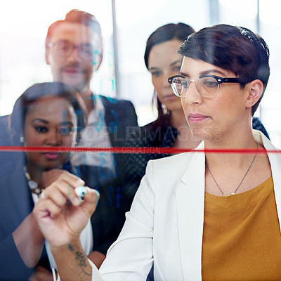 Buy stock photo Cropped shot of a businesswoman writing on a glass wall while her colleagues look on