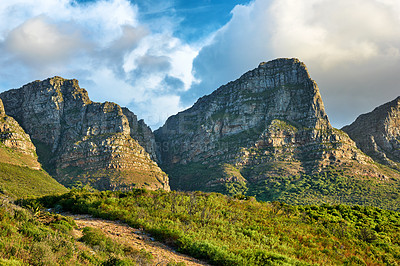 Buy stock photo Landscape of a mountain in Cape Town, South Africa in the day. Rocky mountaintop with greenery against cloudy sky. Below of popular tourist attraction and adventure hiking trail near table mountain